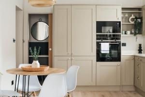 a kitchen with white cabinets and a table and chairs at Light & Luxury London Apartment in Honor Oak in London