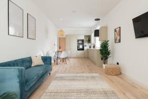 a living room with a blue couch and a kitchen at Light & Luxury London Apartment in Honor Oak in London