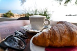 una tazza di caffè e un cornetto su un tavolo di Testa di Monaco Natural Beach a Capo dʼOrlando