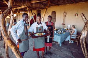 a group of three men holding a tray of food at Maji Moto Eco Camp in Maji Moto
