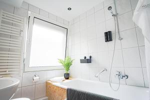 Baño blanco con bañera y lavamanos en HOMEFY BRIGHT AND COZY HOLIDAY APARTMENT, en Essen