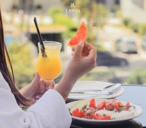 a woman holding a slice of watermelon and a drink at La Onda Hotel Durres in Durrës