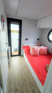 una camera da letto con un letto rosso e una grande finestra di Houseboat Water Boy apartament pływający dom na wodzie łódź a Uraz