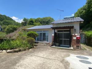 una pequeña casa en un camino de grava en 鉄道と山の見える家, en Yufu