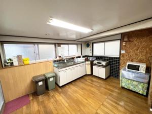 uma grande cozinha com um lavatório e um micro-ondas em 鉄道と山の見える家 em Yufu