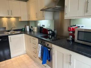 a kitchen with white cabinets and a stove top oven at Nollaig Beachside Bliss - Pass the Keys in Rye