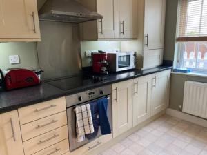 a kitchen with a stove and a microwave at Nollaig Beachside Bliss - Pass the Keys in Rye