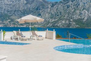 een patio met stoelen en een parasol naast een zwembad bij Lavender Bay Apartment B23 in Kotor