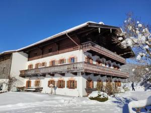 um grande edifício de madeira com uma varanda na neve em Einsiedlhof em Inzell