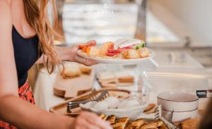 a woman holding a plate of food on a counter at La Onda Hotel Durres in Durrës