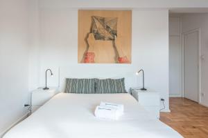 ein weißes Schlafzimmer mit einem weißen Bett und zwei Lampen in der Unterkunft Pratinhas in Porto