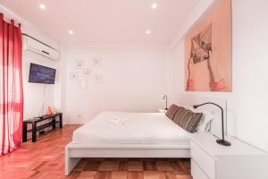 ein weißes Schlafzimmer mit einem weißen Bett und einem roten Vorhang in der Unterkunft Pratinhas in Porto