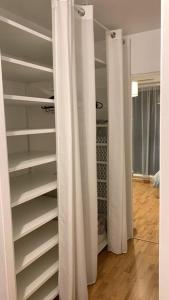 a closet with white shelves and curtains in a room at Cœur de ville Loverien in Louviers