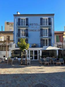 a hotel with tables and chairs in front of it at Hôtel de la Corniche d'Or in Mandelieu-La Napoule