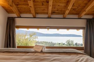 Dormitorio con ventana y libro en la cama en Colago Private Villas Lake Garda, en Toscolano Maderno