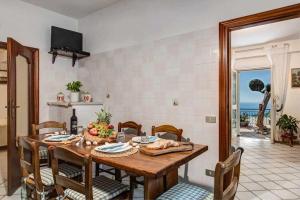 une salle à manger avec une table, des chaises et une télévision dans l'établissement Ulivello Country Side Apartment with Sea View, à Massa Lubrense