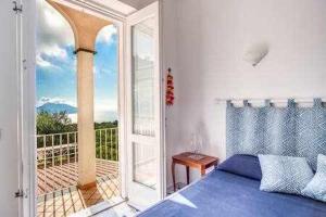 a bedroom with a blue bed and a balcony at Campanella Villas Gardens Pool Superview in Termini