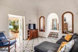 a living room with a couch and a tv at Campanella Villas Gardens Pool Superview in Termini