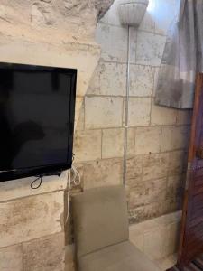 einen Flachbild-TV an einer Steinmauer mit einem Stuhl in der Unterkunft Muzepotamia Butik Otel in Şanlıurfa