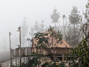 een huis op een heuvel in de mist bij De Chia Campsite in Mèo Vạc