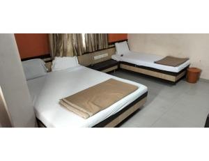 2 Betten in einem kleinen Zimmer mit ermottermottermott in der Unterkunft Shangrila's Hotel Sai Chandra in Shirdi