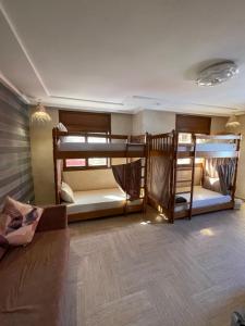 a room with three bunk beds and a couch at ASNFU AUBERGe in Imsouane