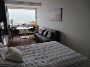 una camera da letto con un letto, un divano e un tavolo di Studio Albert met prachtig zeezicht a Ostenda