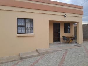 ein kleines Haus mit einem Tisch und einem Fenster in der Unterkunft Be-My-Guest Holiday Apartment in Maseru