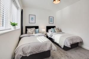 two beds in a room with white walls and a window at Luxury 2-Bedroom Formby Property in Formby