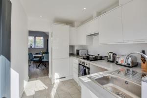 a white kitchen with a sink and a table at Luxury 2-Bedroom Formby Property in Formby