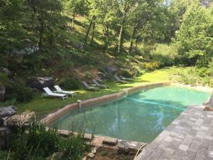 a swimming pool with lounge chairs in a yard at Le Moulin en Provence in Saint-Antonin-sur-Bayons