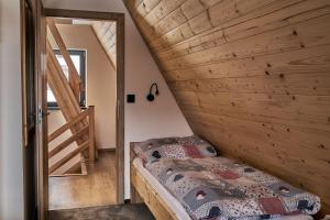 een slaapkamer met een bed en een houten muur bij Resort Bobrovník in Lipova Lazne