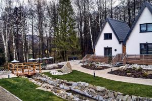 a white house with a stone wall and a yard at Resort Bobrovník in Lipova Lazne