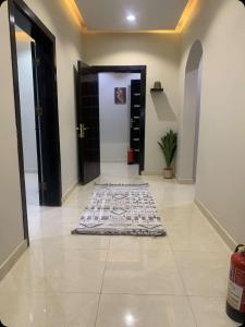 a hallway with a door and a rug on the floor at أجنحة رونق العلا 2 in Al-ʿUla