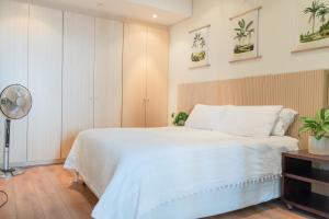 a bedroom with a white bed and a fan at Japandi x Jungle Apartment in Cape Town