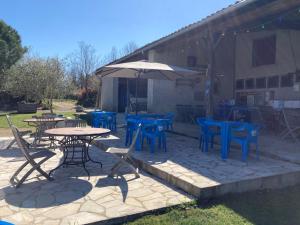 a patio with tables and chairs and an umbrella at Camping Fargogne in Puygaillard-de-Quercy