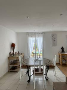 a white dining room with a table and chairs at Charmante Maison entre châteaux et océan in Cussac-Fort-Medoc