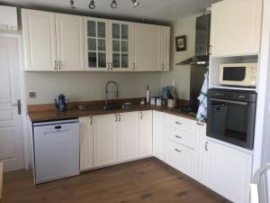 a kitchen with white cabinets and white appliances at Charmante Maison entre châteaux et océan in Cussac-Fort-Medoc +6 photos