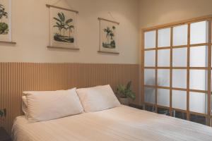 een slaapkamer met een bed met witte lakens en een raam bij Japandi x Jungle Apartment in Kaapstad