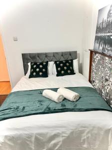 a bed with two pillows and two towels on it at Cosy Home Stay in London
