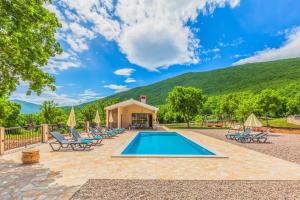 a pool with chaise lounge chairs and a house at Villa Patria with Media room, Private pool, Summer kitchen, Gym in Lovreć