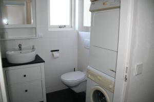 a white bathroom with a toilet and a sink at Lamsoor 9C in Nieuwvliet +14 photos