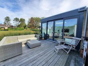 a large deck with a couch and chairs on it at Lamsoor 9C in Nieuwvliet