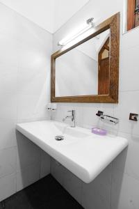 La salle de bains est pourvue d'un lavabo blanc et d'un miroir. dans l'établissement Villa Jungle & Wiener, à Habaraduwa Central