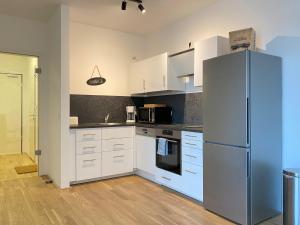 a kitchen with white cabinets and a refrigerator at Bootshaus Am Neuen Hafen in Bremerhaven