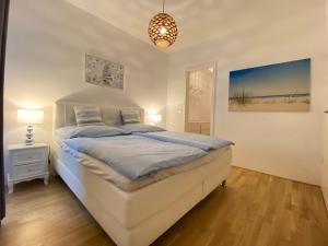 a white bedroom with a bed and a pendant light at Bootshaus Am Neuen Hafen in Bremerhaven