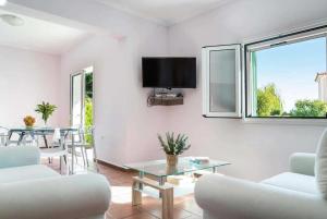 a living room with white furniture and a tv on the wall at Villa Olga in Katelios