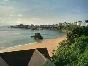a beach with a rock in the water at Glenholme Apartments in Tenby