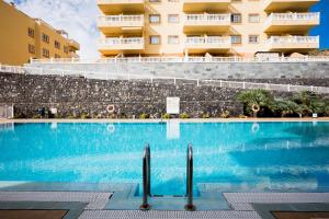 a swimming pool in front of a building at Palm Mar Romantic Suite A21 in Palm-mar