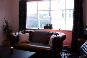 a leather couch in a living room with a large window at Charming apartment in central Stavanger in Stavanger